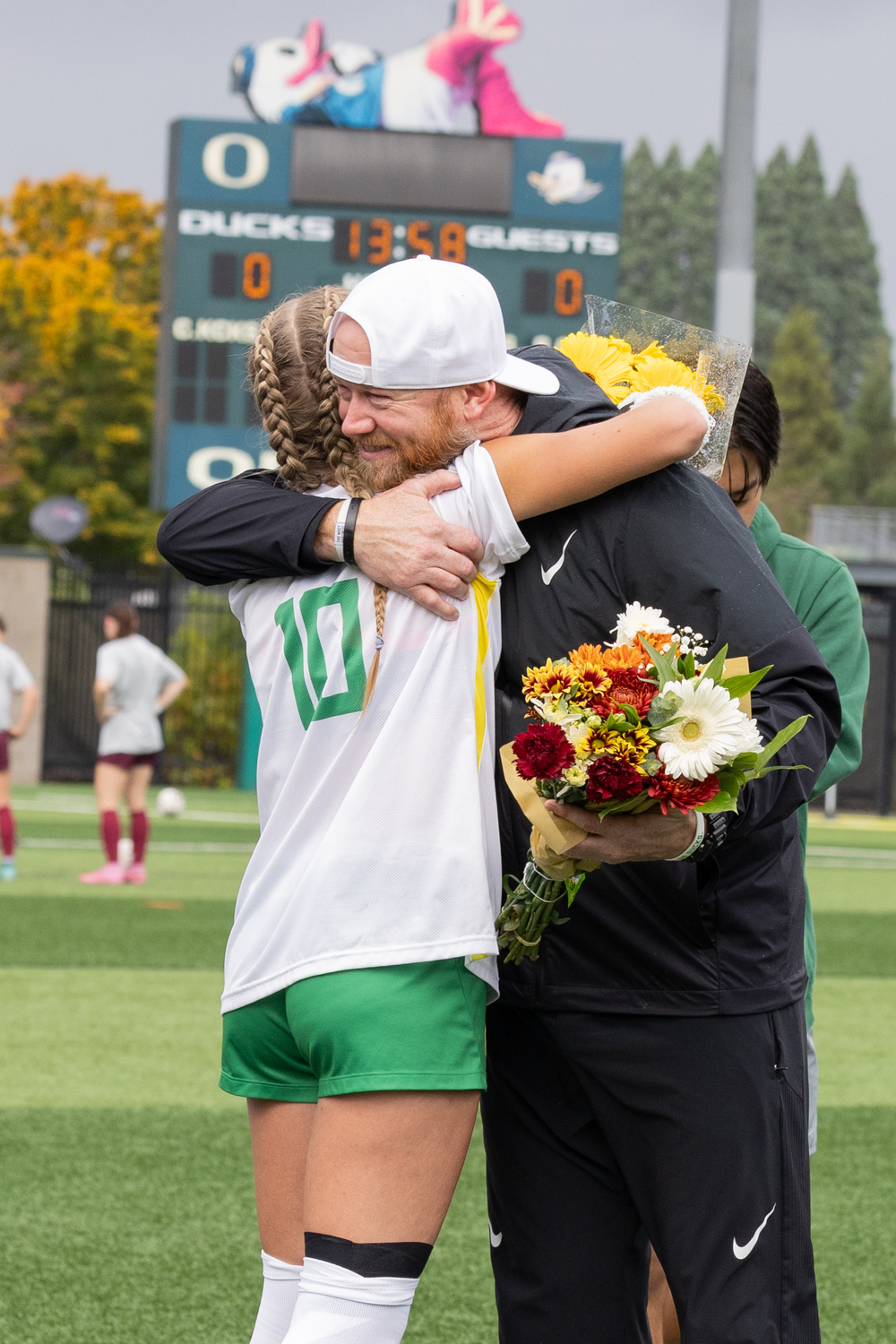 Assitant coach Chris King embraces senior Jayde Holley (10) to celebrate her before Oregon's senior game. The University of Oregon played University of Minnesota at Pape Field in Eugene, Ore., on Oct. 19, 2025. (Owen Burriss/Emerald)