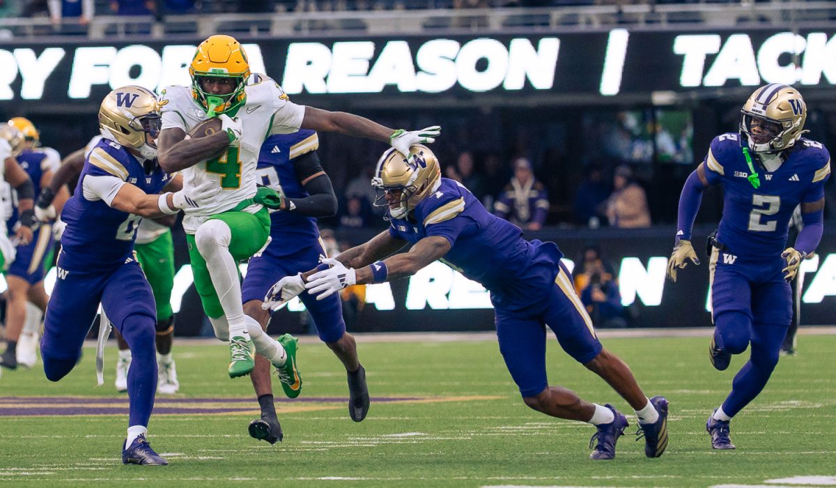 Oregon Ducks wide receiver Malik Benson (4) sprints down the field narrowly dodging two Husky defenders. The No. 4 University of Oregon Ducks defeated the University of Washington Huskies 26-14 at Husky Stadium in Seattle, Wash. on Nov. 29, 2025, securing a College Football Playoff first round game. (Saj Sundaram/Emerald)