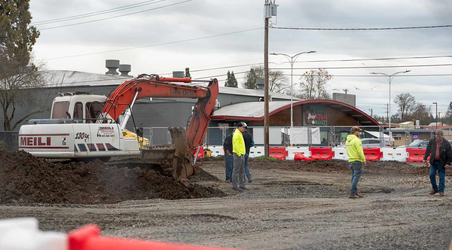 The Whiteaker Commons, an affordable apartment complex is being built on the corner of West Fifth Ave. and Adams St, set to open in 2027. As of currently, Dec. 16, 2025, the former Diamond Parking lot has been reduced to a gravel and dirt lot, with a single excavator in the center. There are a few construction workers inside the lot, guiding incoming dump trucks full of gravel. (Saj Sundaram/Emerald)