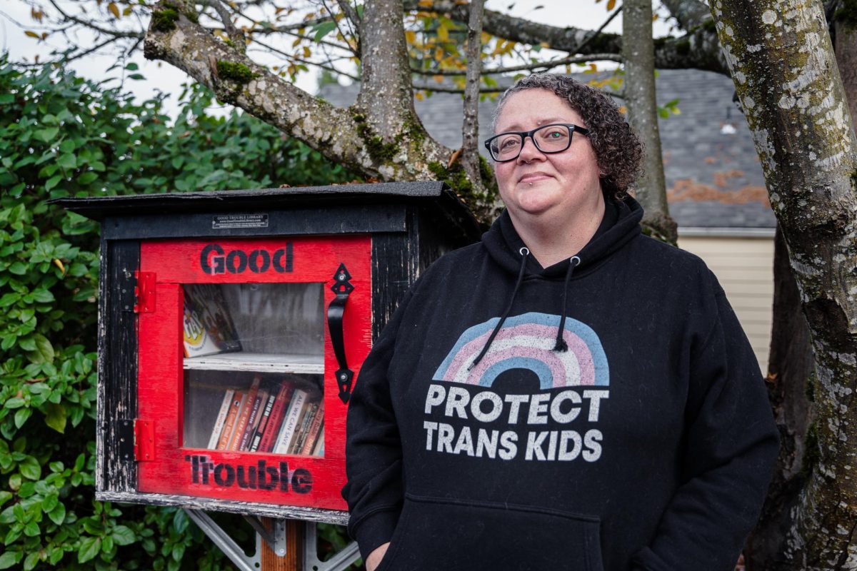 Lifelong Eugene activist Mo Young poses for a headshot next to a Little Free Library filled with books on queer expression, carceral justice and antiracism. The library is painted with
the words “Good Trouble,” a reference to civil rights activist John Lewis.