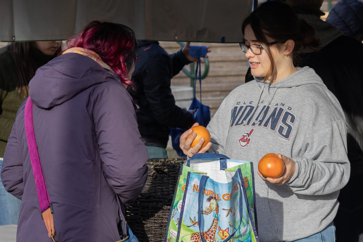 A student worker helps a customer choose between oranges. The University of Oregon hosted its weekly Student Produce Drop in the EMU Amphitheater on January 20, 2026. (Owen Burriss/Emerald)