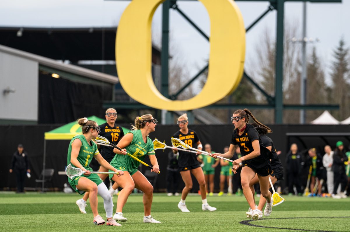 Duck junior attacker Gabby Santucci (12) looks to get around sun devil freshman defender Averie Cage (3). On Feb. 7th, 2026 the University of Oregon women's lacrosse team hosted a season-opening game against Arizona State University on Papé Field in Eugene, Ore. (Katie Poluyansky/Emerald)