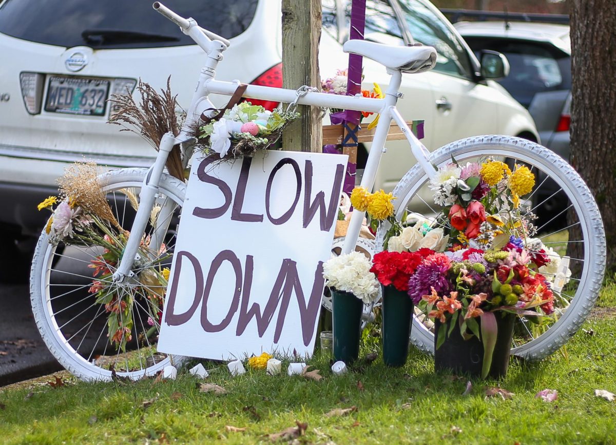 Flowers to remember the loss sit around the bike. A “Ghost Bike” commemorating the recent loss of cyclist Erick Njue sits on the corner of 22nd Avenue and Patterson Street in Eugene, Ore., on Feb. 17, 2026 (Tyler Graham/Emerald)