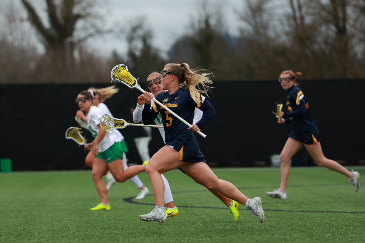 California Golden Bear Annette Ciupek (5) carries the ball up the field and is tracked by Duck Avery Young (15). The University of Oregon women’s lacrosse team hosts the California Golden Bears at Pape Field in Eugene, Ore., on Thursday, Feb. 19, 2026. (Julia Massa/Emerald)