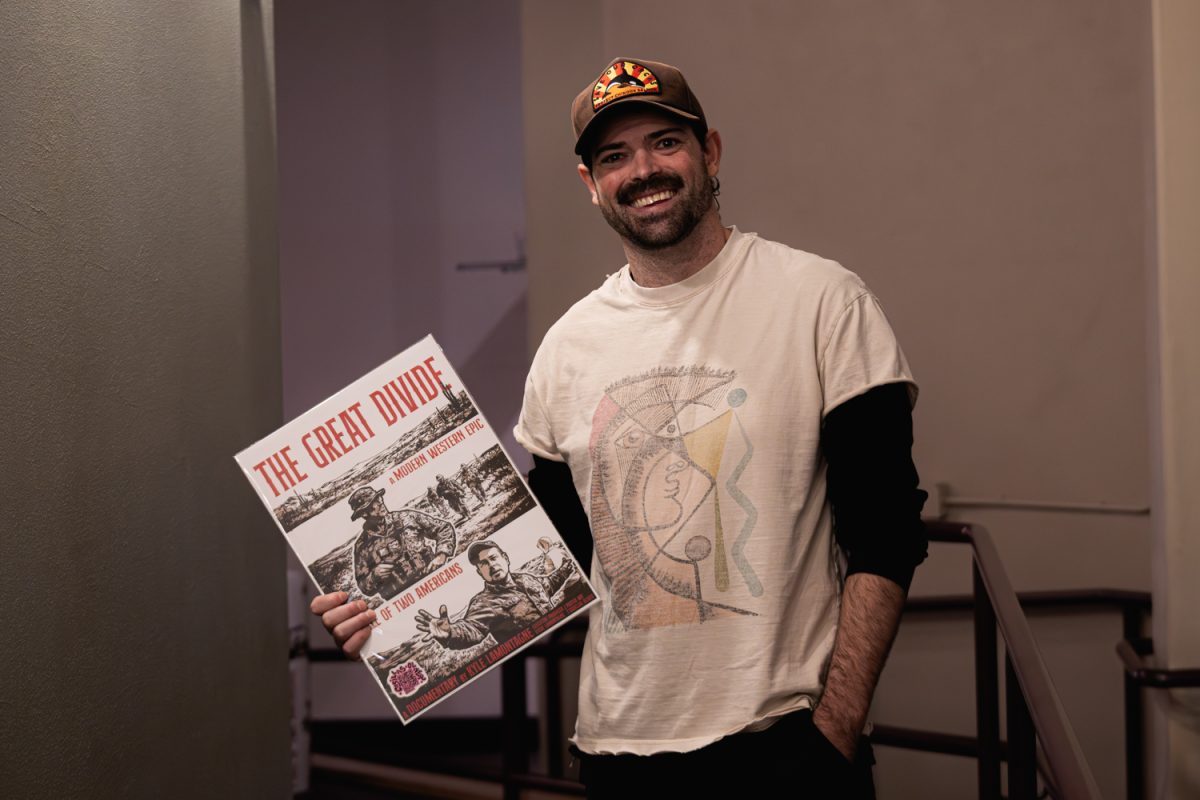 UO Alum Kyle LaMontagne poses with poster for his film 'The Great Divide' during a private premiere on Feb. 21. (Maria Weyne/Emerald)