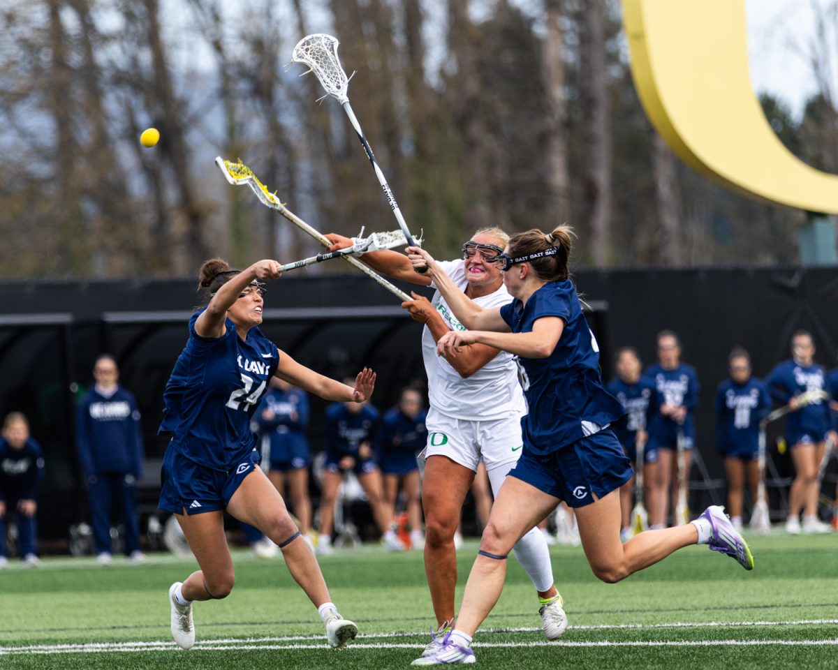 Oregon attacker Avery Young (15) tosses the ball over two UC Davis defenders. The Oregon Ducks women’s lacrosse hosted the UC Davis Aggies at Pape Field in Eugene, Ore. on Feb. 28, 2026, winning 10-9. (Owen Burriss/Emerald)