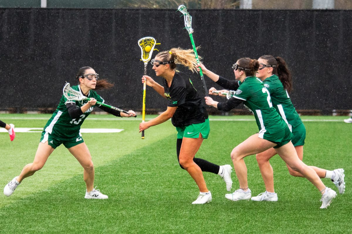 Oregon attacker Gabby Santucci (12) fights through the Eagles crowded defense as she runs up the field. On February 22, 2026, the University of Oregon Ducks took a close loss to the Eastern Michigan University Eagles at Papé Field, at University of Oregon, based in Eugene, Ore. (Fred Hall/Emerald)
