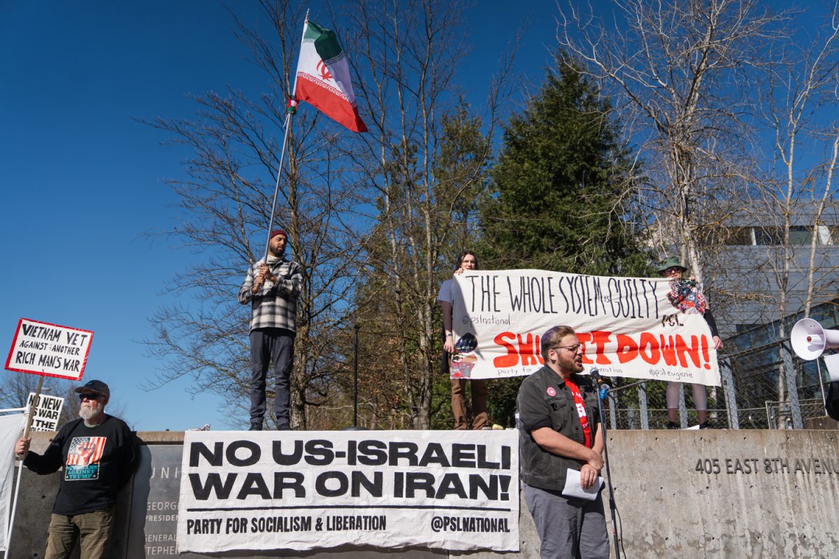 Protestors stand on a ledge outside of the Wayne L. Morse Courthouse in Eugene, Ore. Approximately 75 community members rallied on March 7, 2026, in opposition of the recent strikes on Iran from the Trump administration. (Lilly Wall/Emerald)