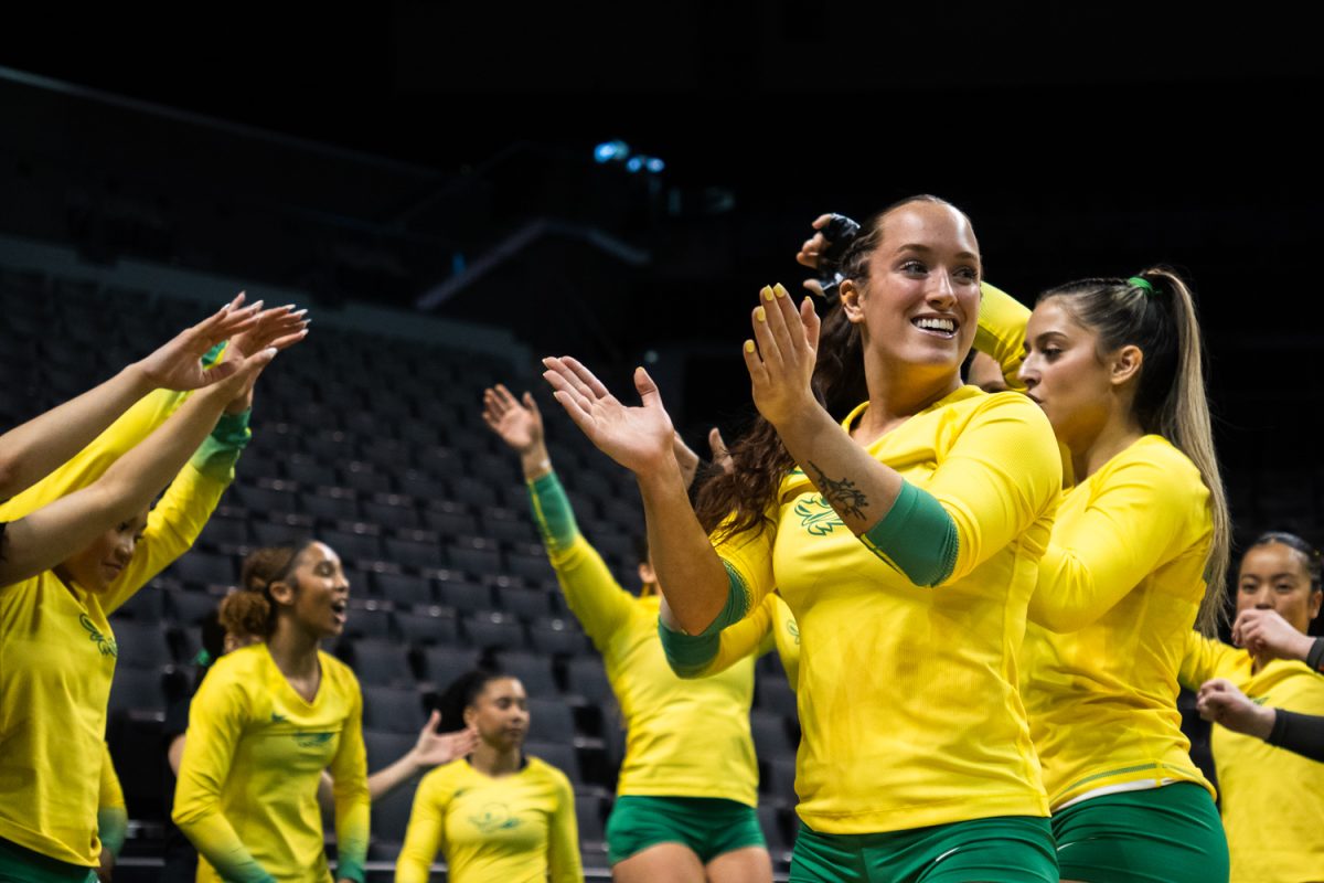Ducks junior tumbler Brynn Mortimer (15) cheers for her teammates as they come off the floor. On March 15, 2026 the University of Oregon Ducks Women’s Acrobatics and Tumbling team beat the Gaels in a tight home meet against Iona University at Matthew Knight Arena in Eugene, Ore. (Katie Poluyansky/Emerald).