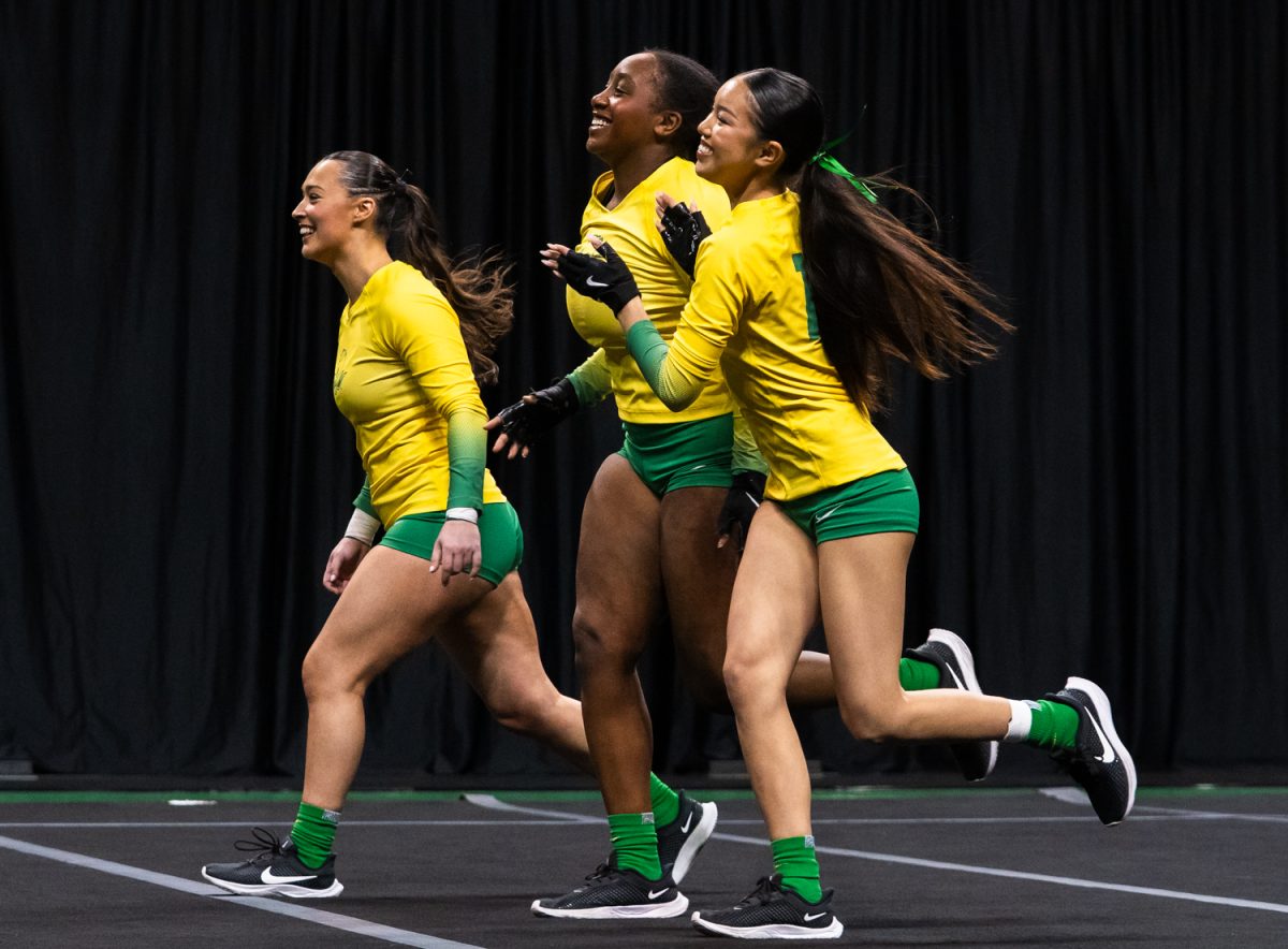 Ducks Angelica Martin (59), Cassidy Cu (19), and Sophia Wing (2) run off the floor with smiles on their face after a successful routine. On March 15,2026 the University of Oregon Ducks Women’s Acrobatics and Tumbling team beat the Gaels in a tight home meet against Iona University at Matthew Knight Arena in Eugene, Ore. (Katie Poluyansky/Emerald).