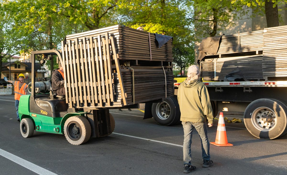 A construction worker uses a forklift to remove the pallets of fencing off the tractor trailer. On April 29, 2026, protesters gathered at the Eugene Federal Building in Eugene, Ore. to object to the building of a fence around the building federal agents of the Department of Homeland Security's Federal Protective Services stood guard. (Saj Sundaram/Emerald)
