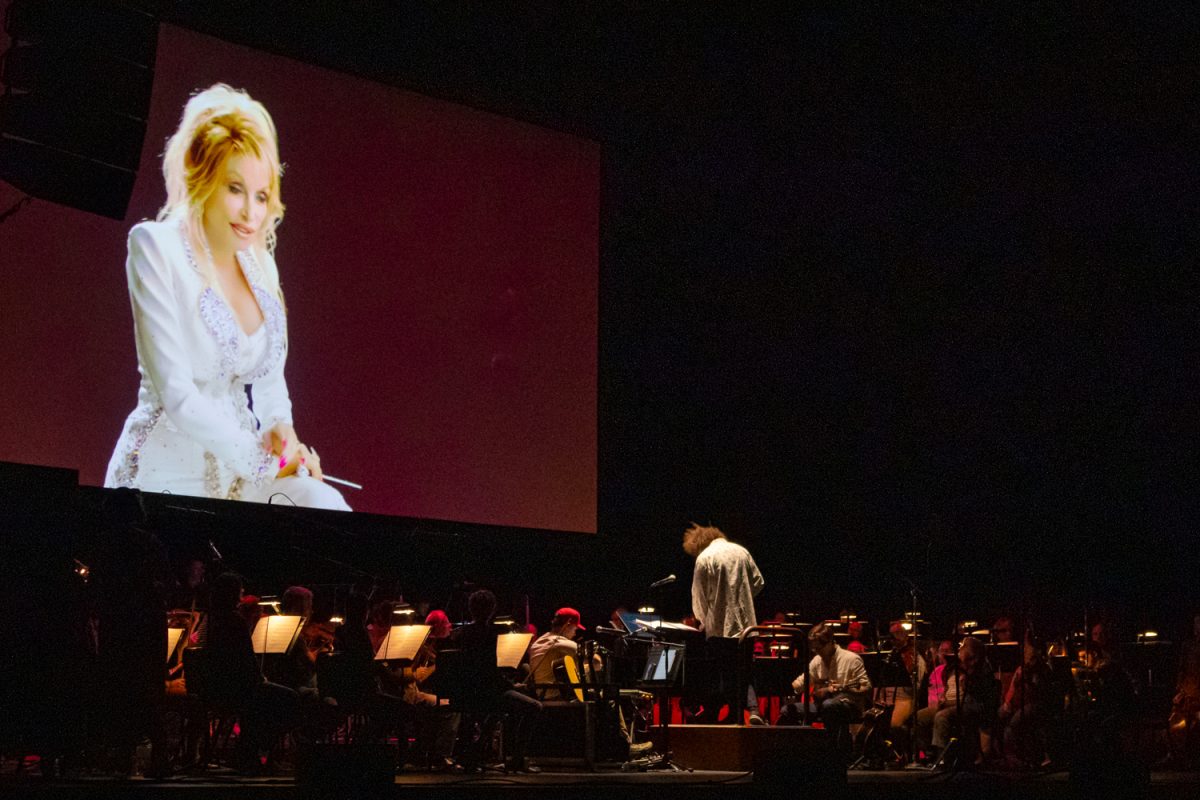 A video of Dolly Parton plays above the Eugene Symphony, conducted by Artistic Director Alex Prior, during a rehearsal for Parton’s “Threads: My Songs in Symphony” at the Hult Center on April 30, 2026. The concert is part of a multimedia touring production that brings some of Parton’s biggest hits to life. (Corey Hoffman/Emerald)