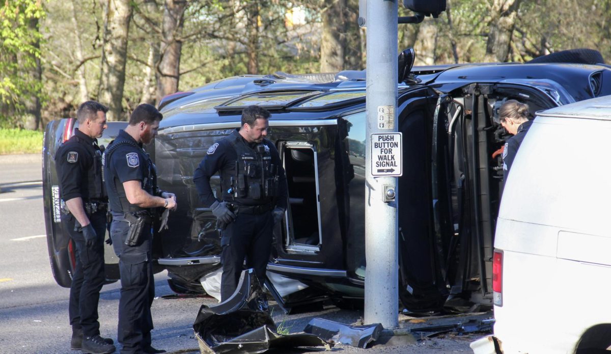 Eugene police officers gather around an overturned vehicle at the intersection of East 11th Avenue and Franklin Boulevard in Eugene, Ore., following a crash that closed nearby roads on Friday, April 3, 2026. (Tarek Anthony/Emerald)