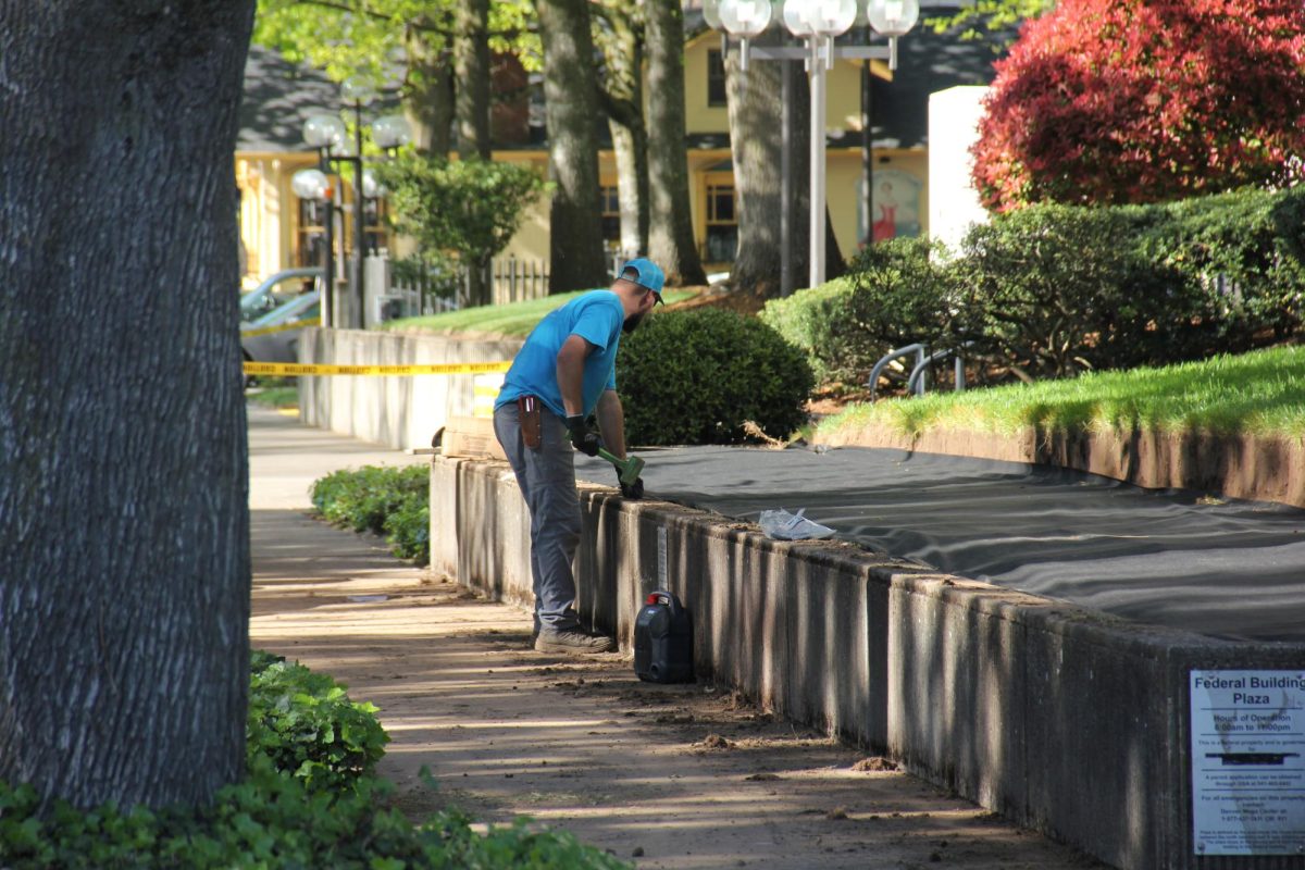 A construction worker prepares to woodchip a flower bed on the west side of the Eugene Federal Building as crews prepare to build a fence on April 29, 2026. (Tarek Anthony/Emerald)
